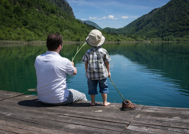 Papà e figlio felici sulle vacanze estive divertendosi e tempo felice vicino al lago della montagna