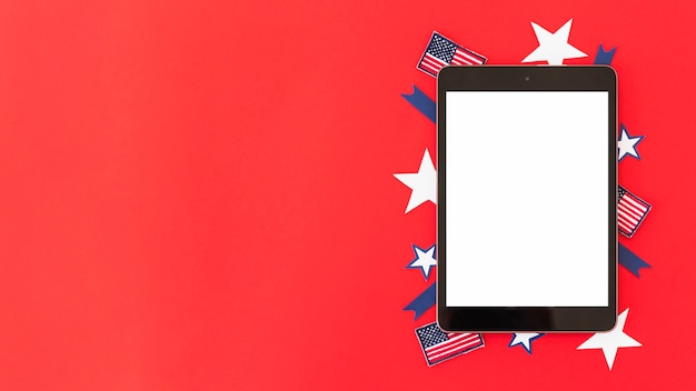 Free photo tablet with decorative elements of american flag on red surface