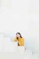 무료 사진 흰 벽에 서있는 사려 깊은 여자