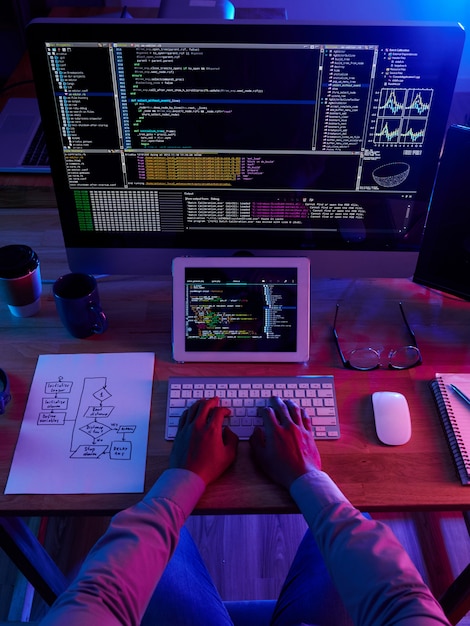 Бесплатное фото Вид сверху неузнаваемого хакера, выполняющего кибератаку ночью