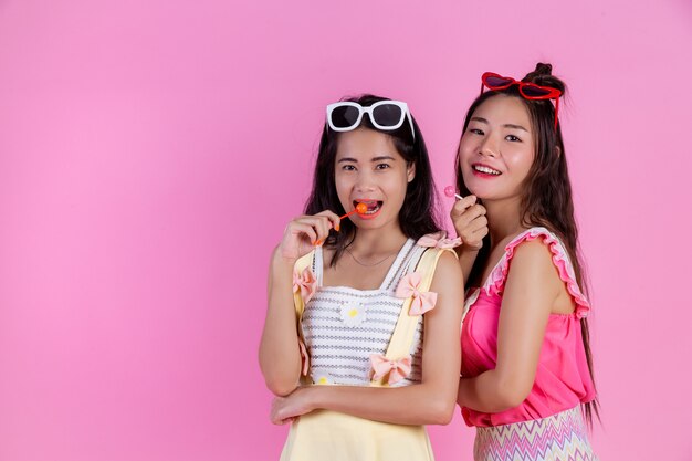 Two Asian girls who are friends are happy and have a pink .
