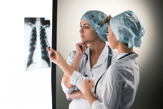 Бесплатное фото Два привлекательных молодых доктора, смотрящие на результаты рентгена