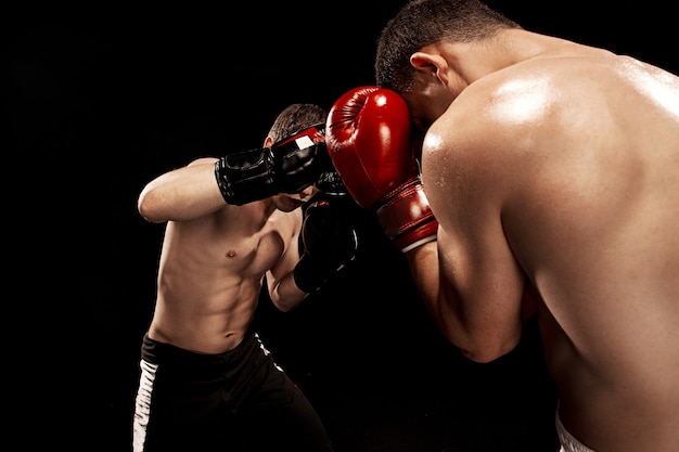 Бесплатное фото Два профессиональных боксера боксируют на черной стене