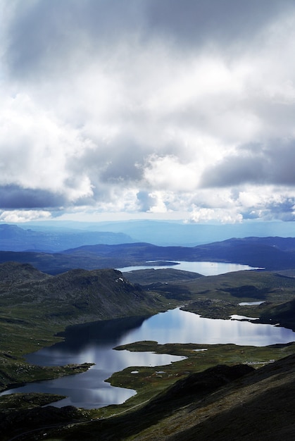 Бесплатное фото Вертикальный вид под высоким углом на пейзаж с рекой на холмах в туддал гаустатоппен, норвегия
