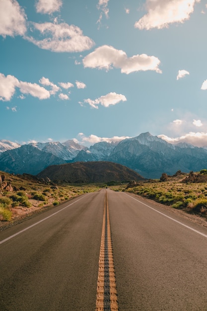 Бесплатное фото Вертикальный снимок дороги с великолепными горами под голубым небом в калифорнии.