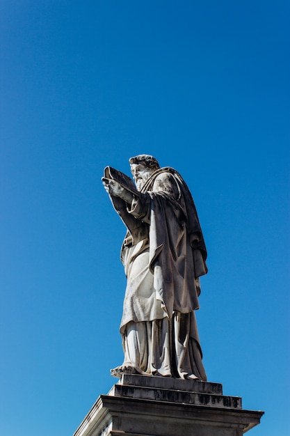 Foto gratuita colpo verticale di una statua storica antica che tocca il chiaro cielo blu