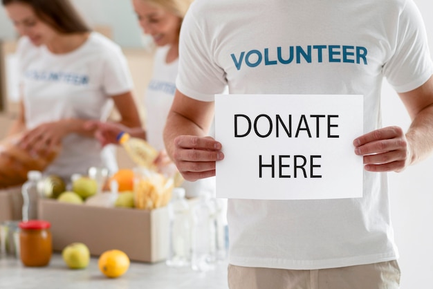 Бесплатное фото Волонтер держит плакат с инструкциями по пожертвованию