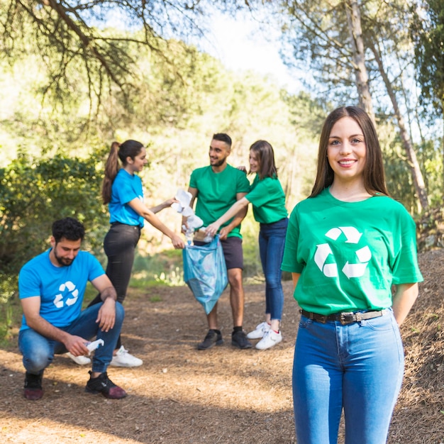 Бесплатное фото Добровольцы складывают мусор в полиэтиленовом пакете в лесу