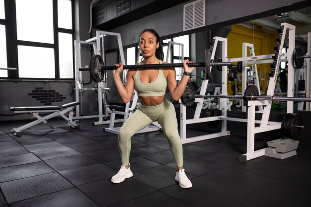Тренировка женщины по тяжелой атлетике в тренажерном зале