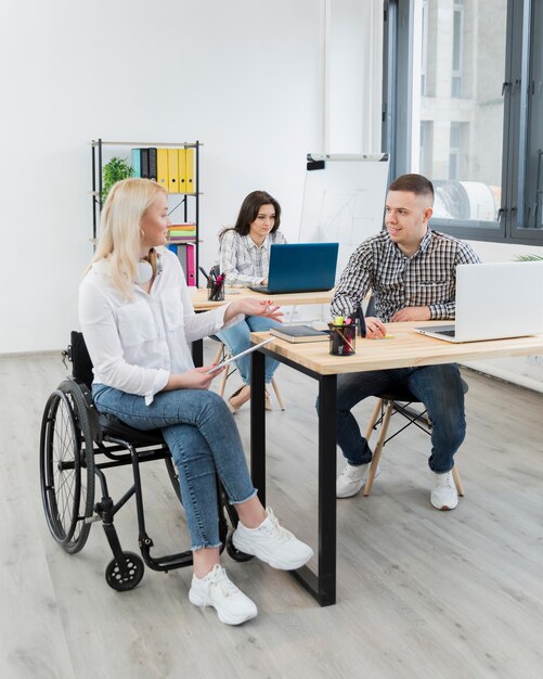 Женщина в инвалидной коляске, обсуждает с коллегой на стол