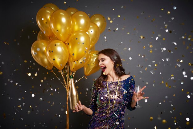 Женщина с воздушными шарами и шампанским среди конфетти