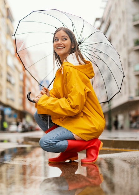 Бесплатное фото Женщина с зонтиком, стоя в дождь сбоку