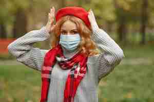 Бесплатное фото Женщина в осеннем лесу. человек в маске. тема коронавируса. дама в красном шарфе.