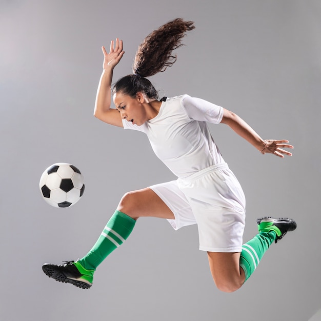 Женщина в спортивной одежде играет в футбол