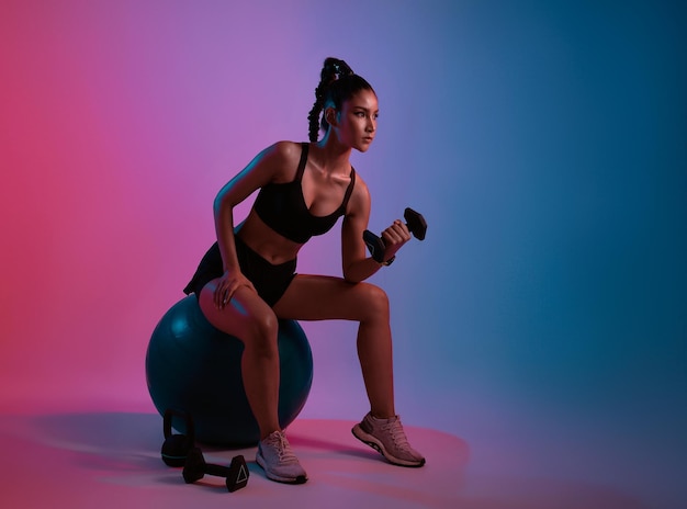 Бесплатное фото Тренировка молодой азиатской женщины, занимающейся тяжелой атлетикой с гантелями в фитнесе