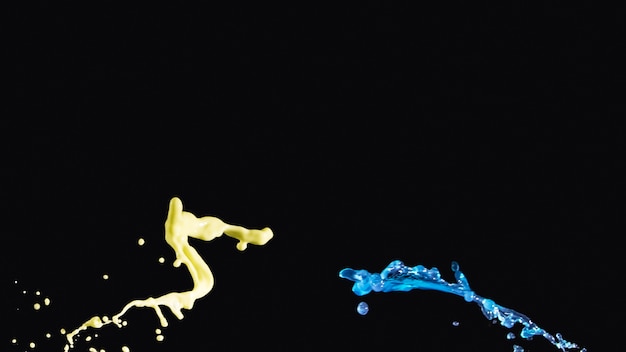 Free photo yellow and blue liquid splashing on opposite side