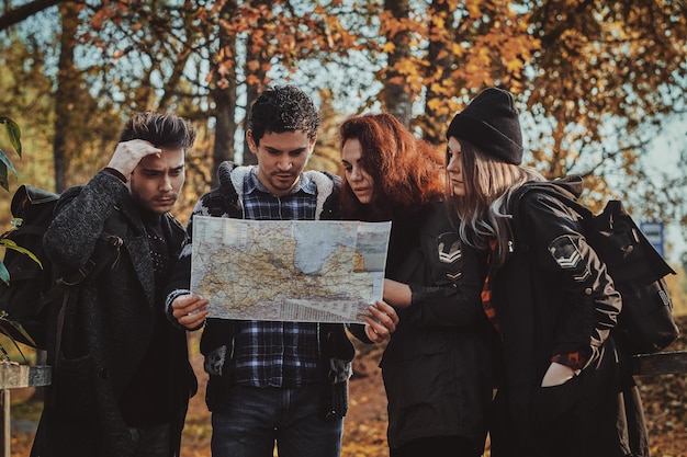 Бесплатное фото Юные туристы, мужчины и женщины пытаются понять, где они находятся, используя карту.