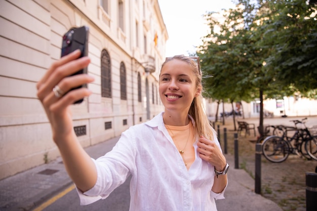 Бесплатное фото Молодая женщина с телефоном улыбается городу