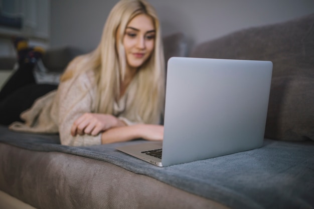 Бесплатное фото Молодая женщина, просматривая ноутбук на диване