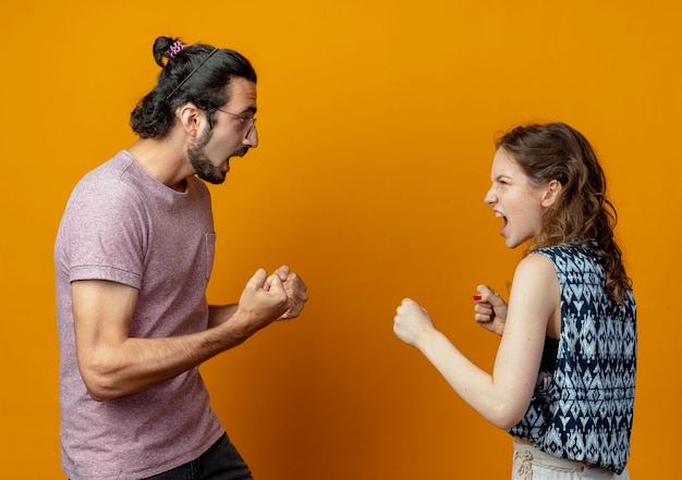 Free photo young beautiful couple man and women quarreling and gesturing having fight crazy and frustrated standing over orange background