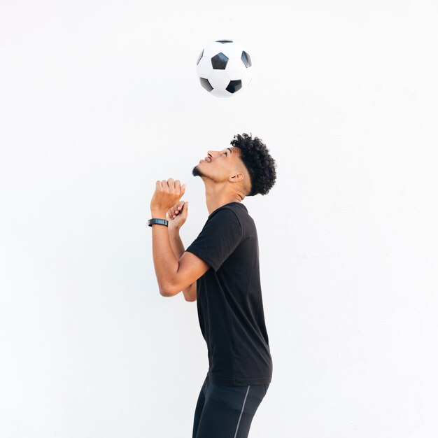 Молодой черный человек жонглирует футбольным мячом