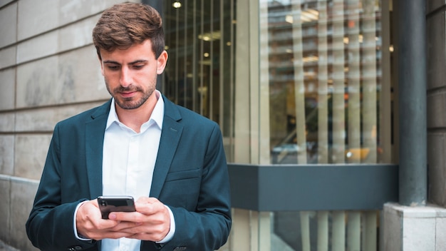Молодой бизнесмен текстовых сообщений на смартфоне