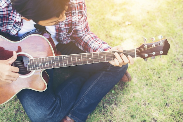 Молодой человек, битник практикуется на гитаре в парке, счастливым и наслаждаться р