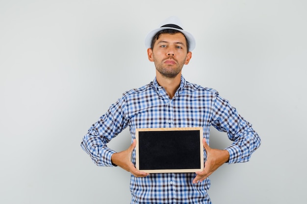 Young man holding blank frame in checked shirt