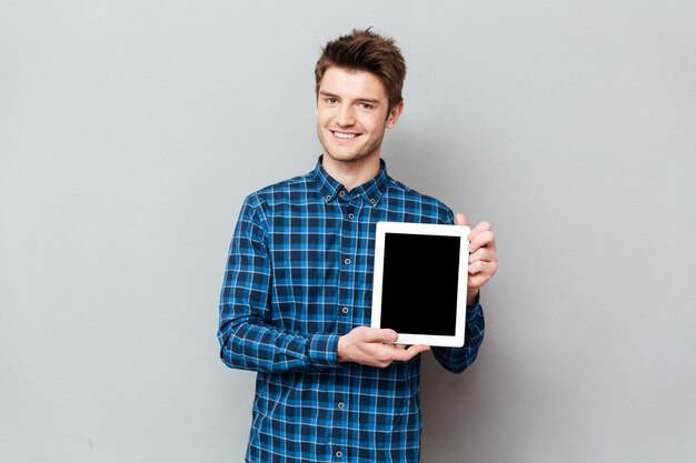Young man showing blank screen of tablet computer isolated