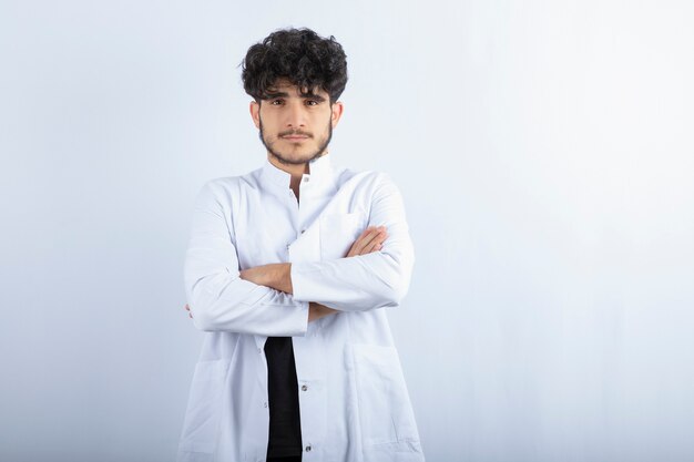 Foto gratuita giovane medico maschio in piedi sul muro bianco.