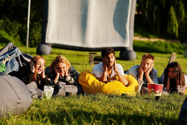 Бесплатное фото Молодая мультиэтническая группа людей смотрит фильм в кинотеатре под открытым небом