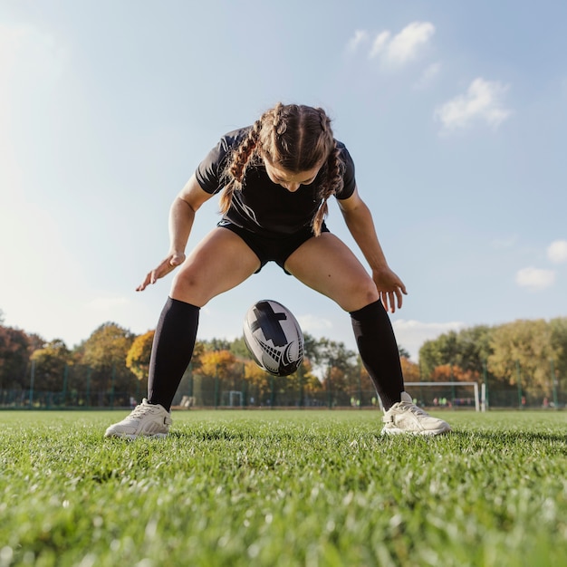 Free photo young sportive girl dropping a rugby ball