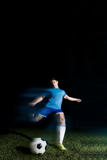 Бесплатное фото Молодой спортсмен пинает футбольный мяч