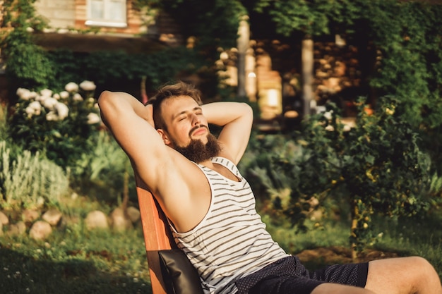 Бесплатное фото Человек отдыхает в загородном доме. бородатый человек наслаждается закатом на зеленой лужайке.