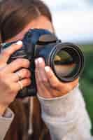 Бесплатное фото Молодая женщина с профессиональной камерой фотографирует на природе