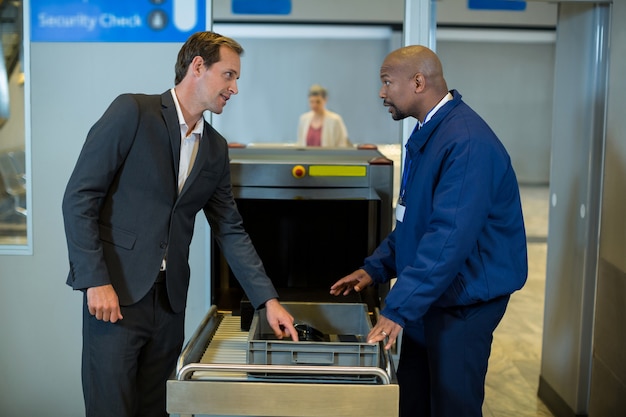 Free photo airport security officer interacting with commuter while checking a package