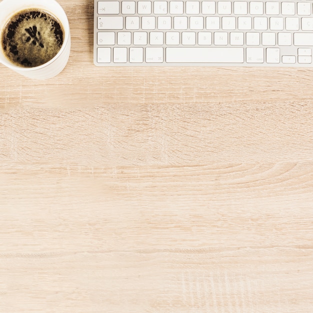 Бесплатное фото Вид сверху кружка кофе и клавиатура на деревянном столе