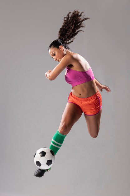 Атлетическая женщина пиная футбол
