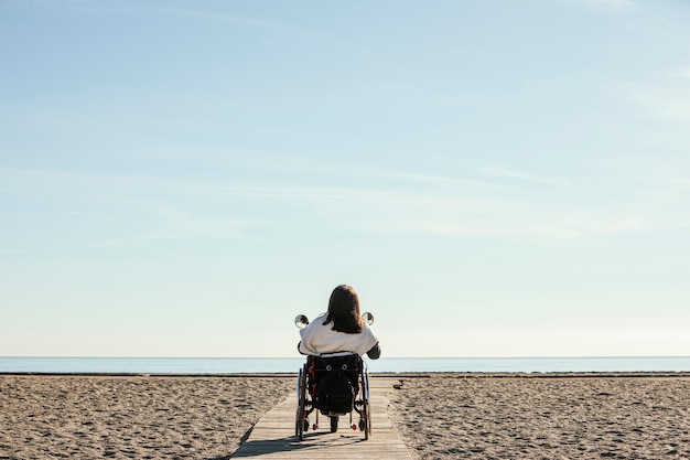 무료 사진 해변에서 휠체어에 여자의 뒷면