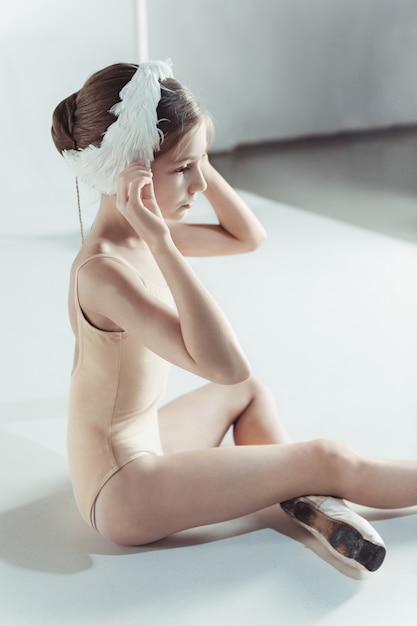 Foto gratuita bella piccola ballerina che indossa una benda di cigno bianco in testa