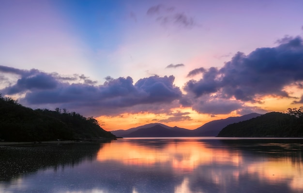 Free photo beautiful scenery of a lake surrounded by forested mountains under a purple sky at sunset