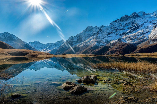 Бесплатное фото Красивый снимок кристально чистого озера рядом со снежной горной базой в солнечный день