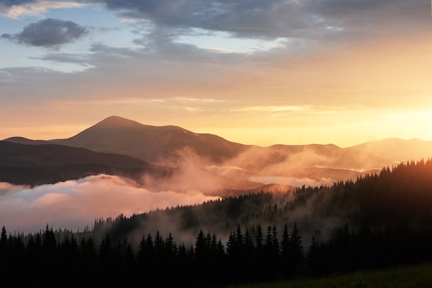 Бесплатное фото Красивый закат в горах. пейзаж с солнечным светом сквозь оранжевые облака и туман.