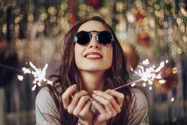 Free photo beautiful woman holding sparklers in hands