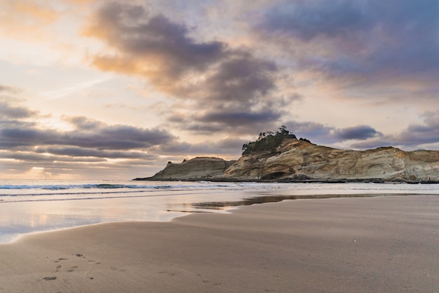 Бесплатное фото Красивый широкий выстрел из скалы у моря с песчаным берегом под небом с облаками