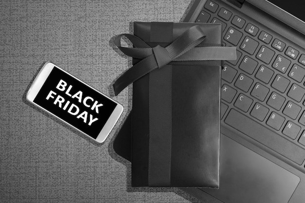 Бесплатное фото Черная пятница сообщение на экране мобильного телефона с подарочной коробкой на черном фоне. концепция черной пятницы
