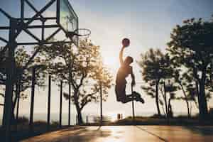 Free photo black man doing sports, playing basketball on sunrise, jumping silhouette