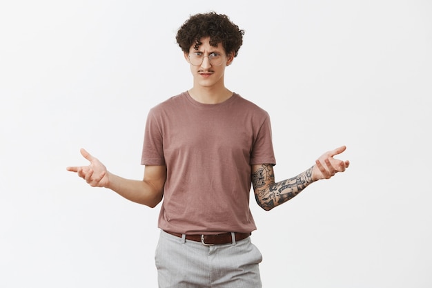 Free photo bro what it means. confused stunned and displeased jewish guy with curly hair and moustache in glasses shrugging with spread palms and frowning being questioned and unaware what is going on