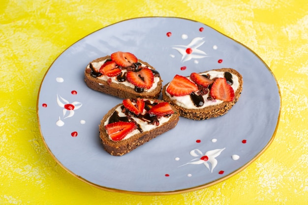Free photo bread toasts with sour cream and strawberries inside blue plate on yellow