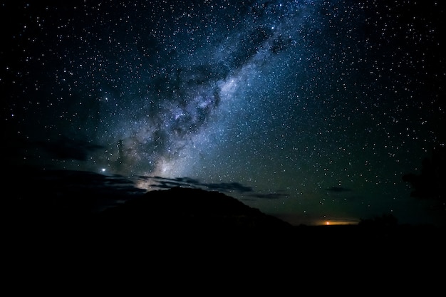 Бесплатное фото Захватывающий снимок силуэтов холмов под звездным небом в ночи.